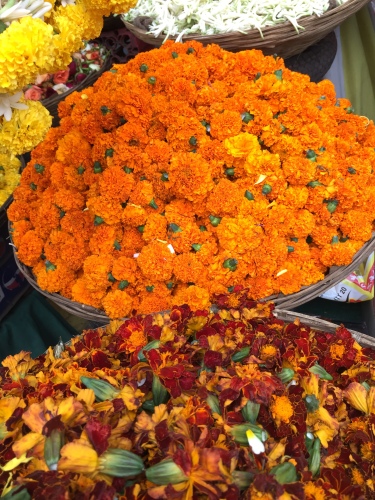 Baskets of different colored Marigolds sold in the market.